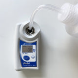 IP65 water-resistant Atago PAL-1 digital handheld refractometer being cleaned or calibrated with distilled water.